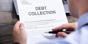 A close-up image of a hand firmly holding a debt collection notice.