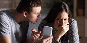 Husband covertly installing spyware on wife's smartphone to monitor her activities.